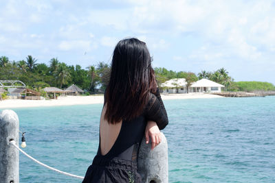 Rear view of woman standing at sea against sky