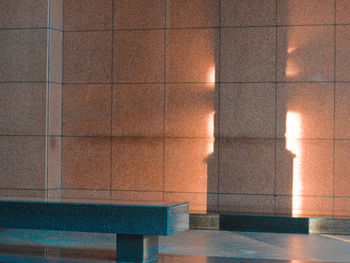 Shadow of empty bench on tiled floor