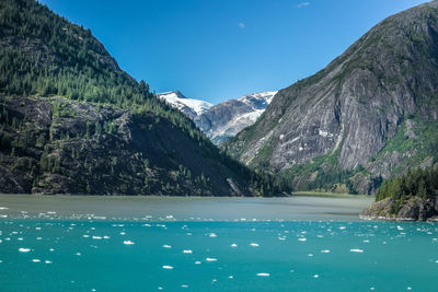 Scenic view of lake by mountains against blue sky