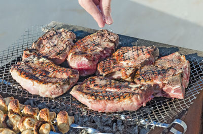 Cooks hand salt the meat on the grill. cooking meat in a barbecue. portioned steaks grilled.