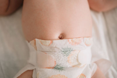 Midsection of baby lying down on bed