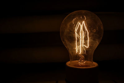 Close-up of illuminated light bulb in darkroom