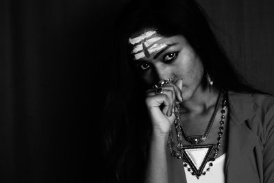 Portrait of beautiful woman holding eyeglasses against black background