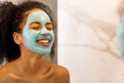 Close-up of smiling woman with facial mask