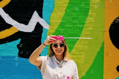 Portrait of smiling young woman standing against wall