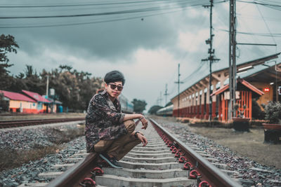 Rear view of man on railroad tracks against sky