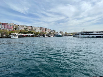 Sea by buildings in city against sky