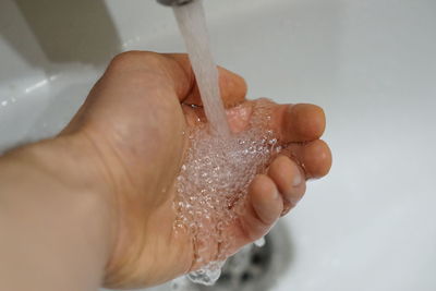 Close-up of human hand touching water in bathroom