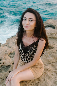 Portrait of young woman sitting on rock