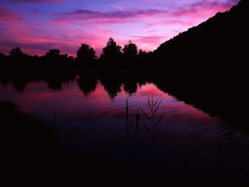 Silhouette trees by lake against sky during sunset