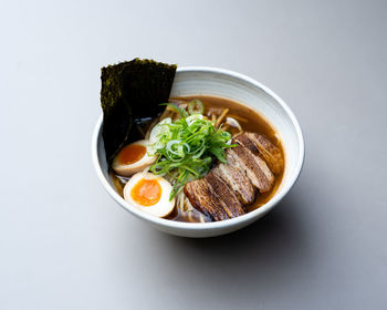 Asian noodle soup, ramen with meat, tofu, vegetables, nori and egg in white bowl