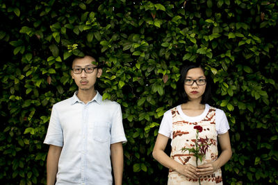 Portrait of young man standing against plants