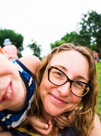 Close-up portrait of smiling mother with son at park