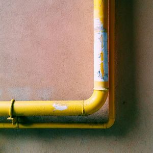 Close-up of yellow pipe against wall