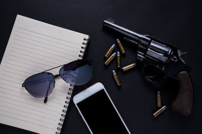 Close-up of sunglasses with weapon and mobile phone on table