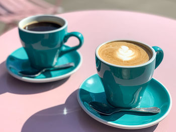 Morning coffees on a pink table. morning coffees in tiffany color ceramic mugs with saucers on pink