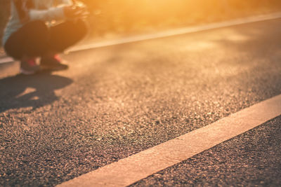Low section of woman on road at sunset