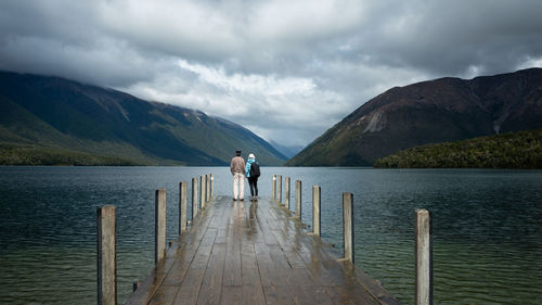 Rear view of man looking at pier against sky