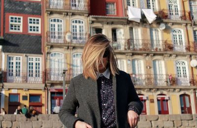 Woman with blond hair standing against buildings