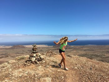 Happy woman dancing on mountain against blue sky