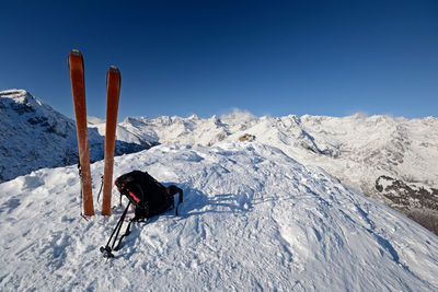 Person skiing on snowcapped mountain against clear blue sky