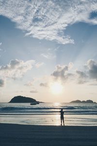 Silhouette man on beach against sky during sunset