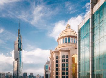 Low angle view of modern building against cloudy sky