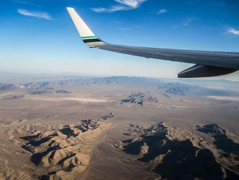 Cropped image of airplane wing flying over mountains