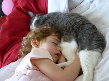 High angle view of baby girl sleeping with cat on bed at home