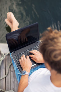 High angle view of man using laptop on pier