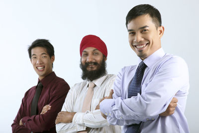 Portrait of smiling businessmen standing against white background