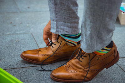 Man binding laces of his leather shoes with happy socks