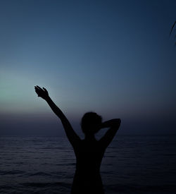 Silhouette woman standing at beach against sky during sunset