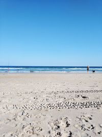 Scenic view of beach against clear blue sky