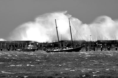 Boats in sea against cloudy sky