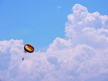 Low angle view of person paragliding in cloudy sky