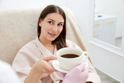 Young woman using mobile phone while sitting on bed at home