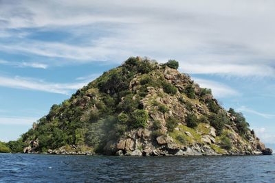 Scenic view of rocks by sea against sky