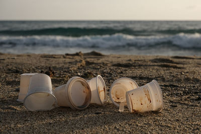 Disposable plastic dirty coffee cups discharged waste,throw pollution,sea shore