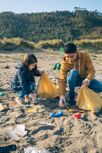 Siblings picking garbage at beach