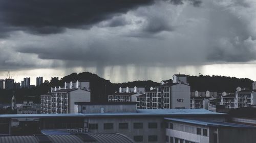 Buildings in city against dramatic sky