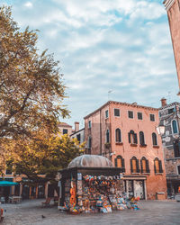 People on street by buildings in city against sky