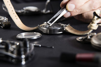 Cropped hand of craftsperson repairing wristwatch at desk