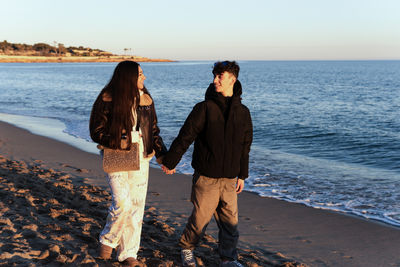 Lovers walking along the beach holding hands at sunset