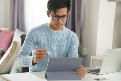 Young man using phone while sitting on table