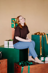 Portrait of smiling young woman sitting on chair against wall