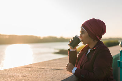 Young woman using mobile phone against sky