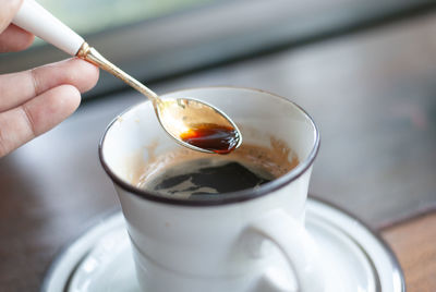 Cropped image of person holding coffee cup on table