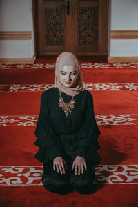 Woman in traditional clothing praying at mosque