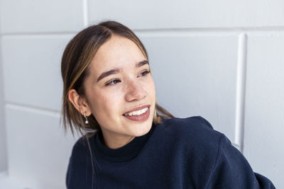 Smiling young woman in front of wall
